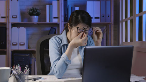Women rubbing eyes in front of computer